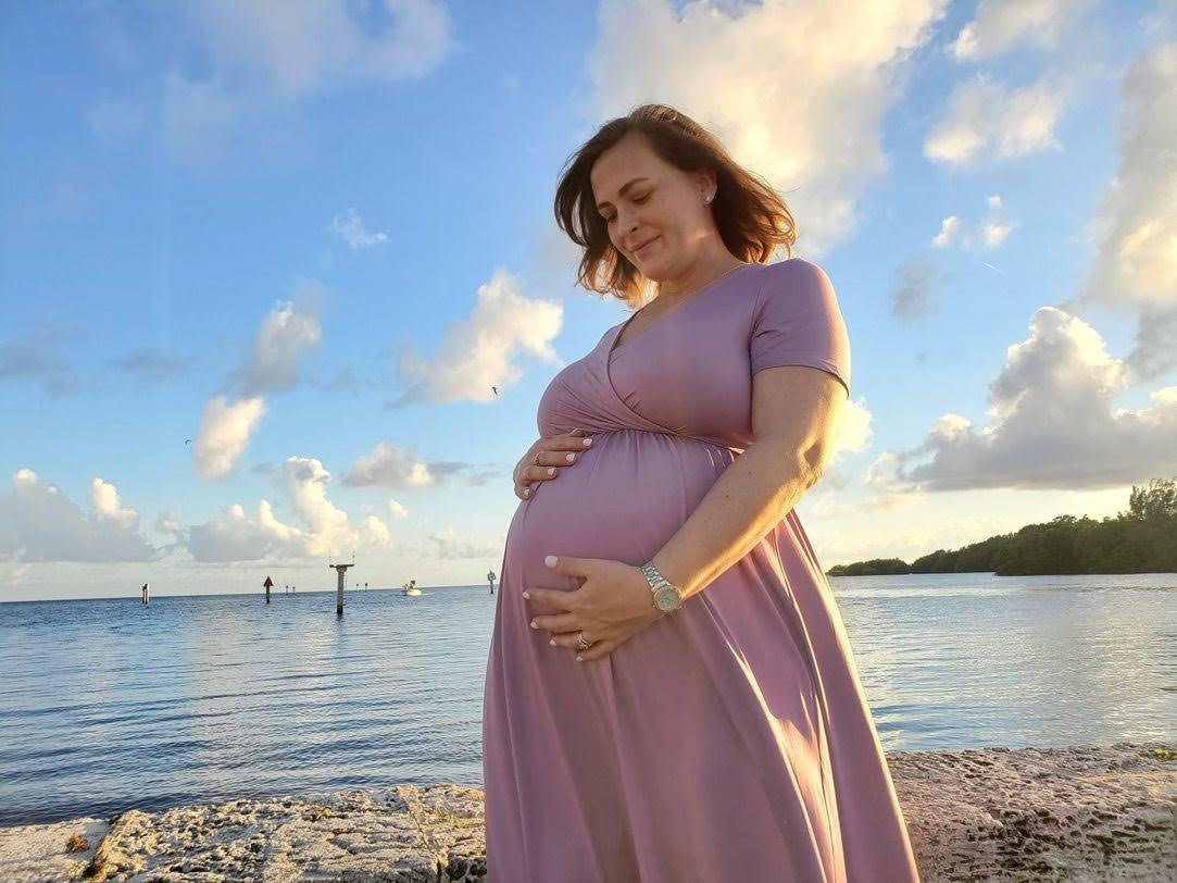 Christy, pregnant, hand resting on her belly at golden hour